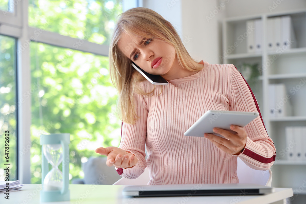 Young businesswoman with tablet computer working under deadline in office