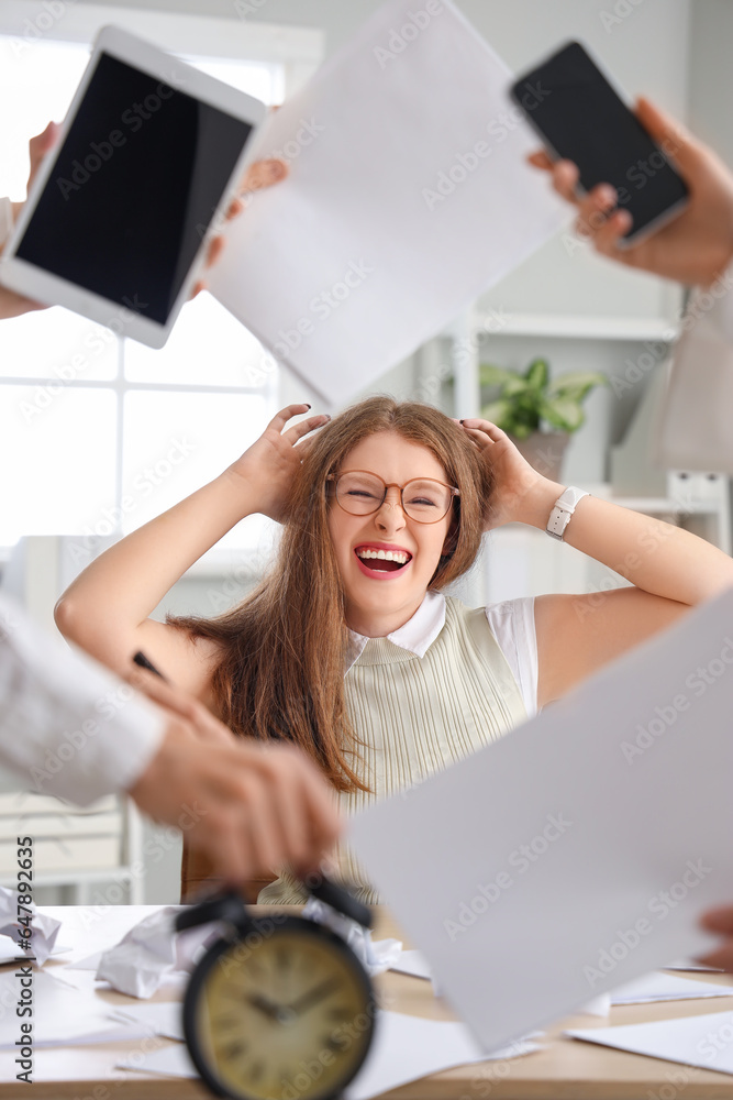 Stressed young businesswoman working under deadline in office