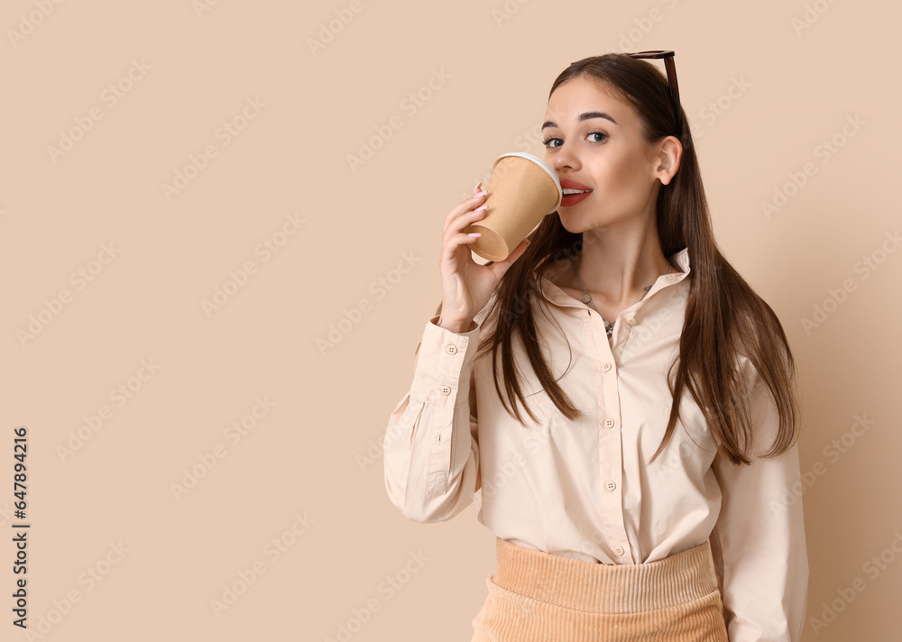 Young woman with cup of coffee on beige background