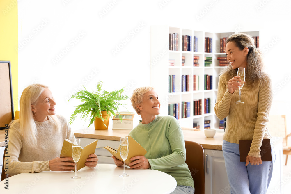 Mature women with champagne taking part in book club at home