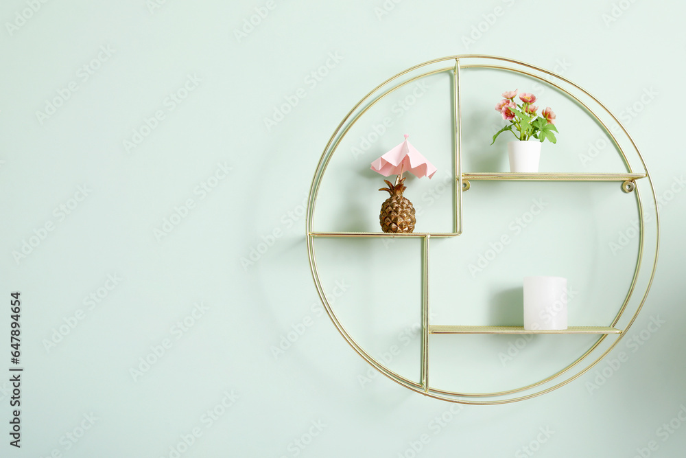 Stylish modern shelf with different home decor on pale green wall