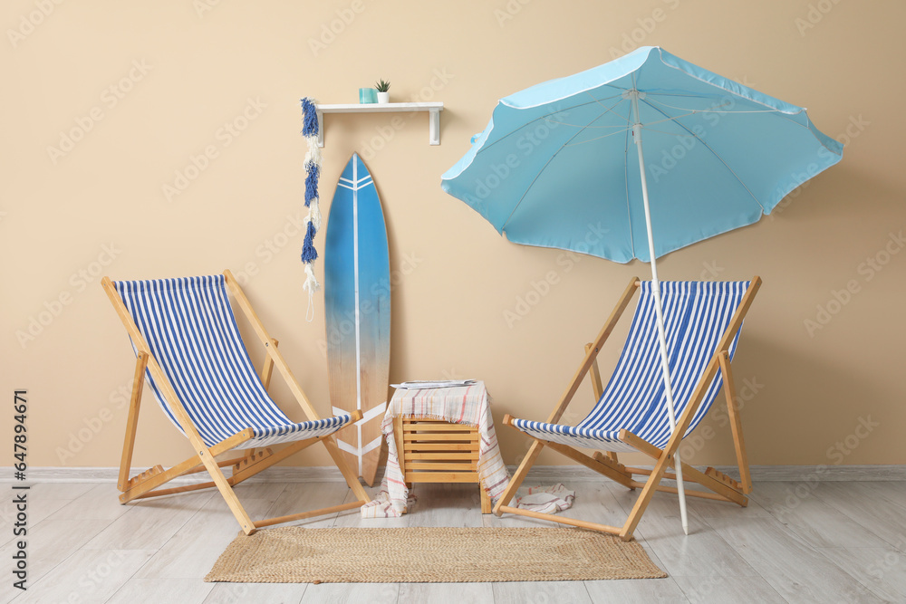 Deckchairs with surfboard and umbrella in stylish room