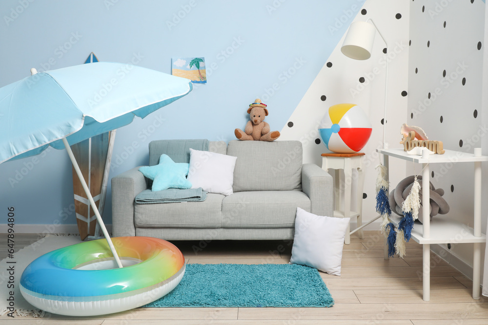 Interior of childrens room with grey sofa and beach accessories