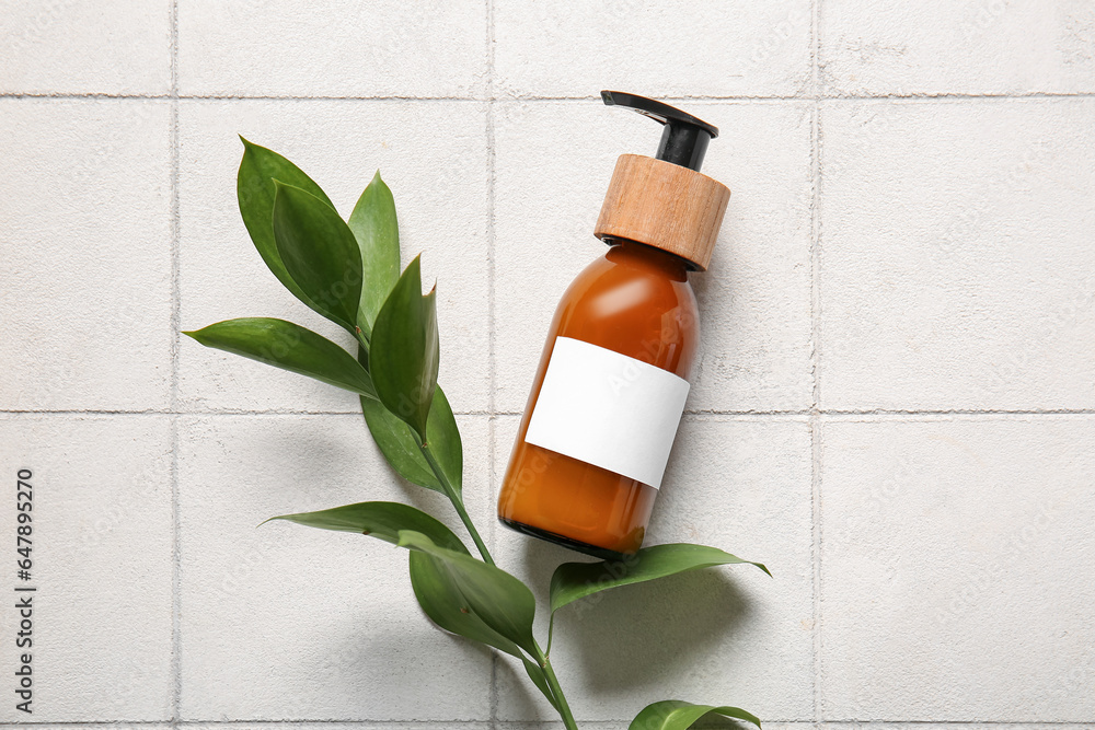 Bottle of shampoo on white tile background