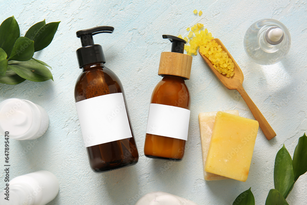 Bottles of shampoo, sea salt, soap bars and cosmetic products on white background