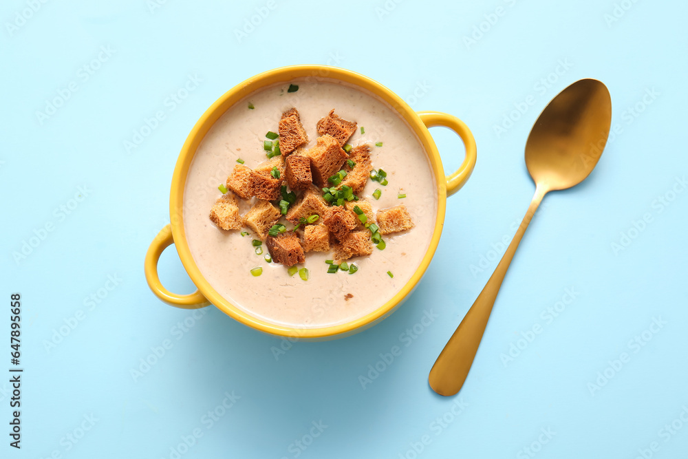 Pot of tasty cream soup with croutons on blue background