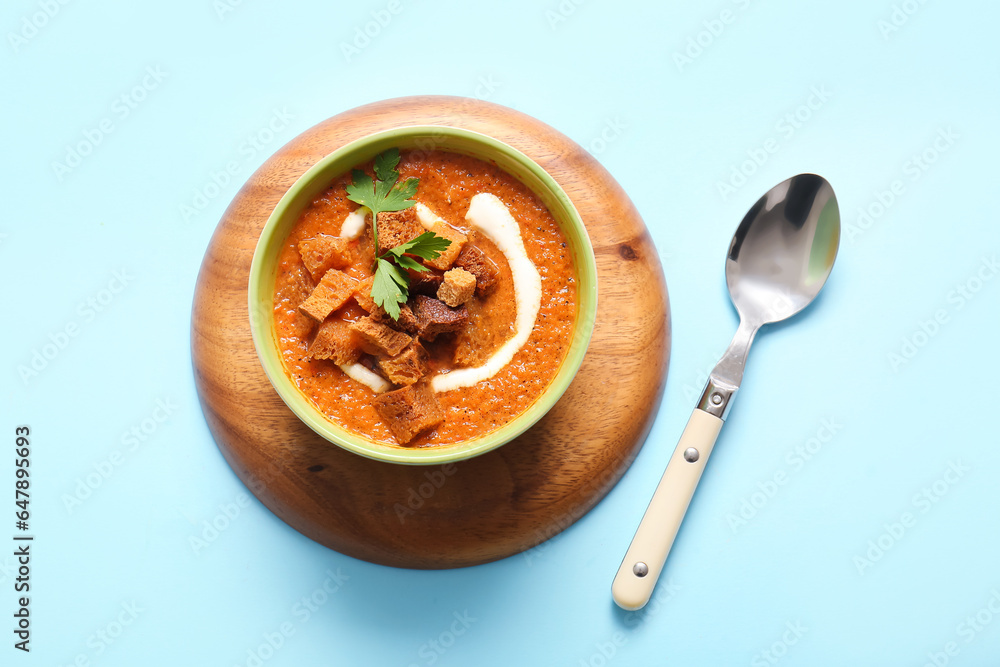 Bowl of tasty cream soup with croutons on blue background