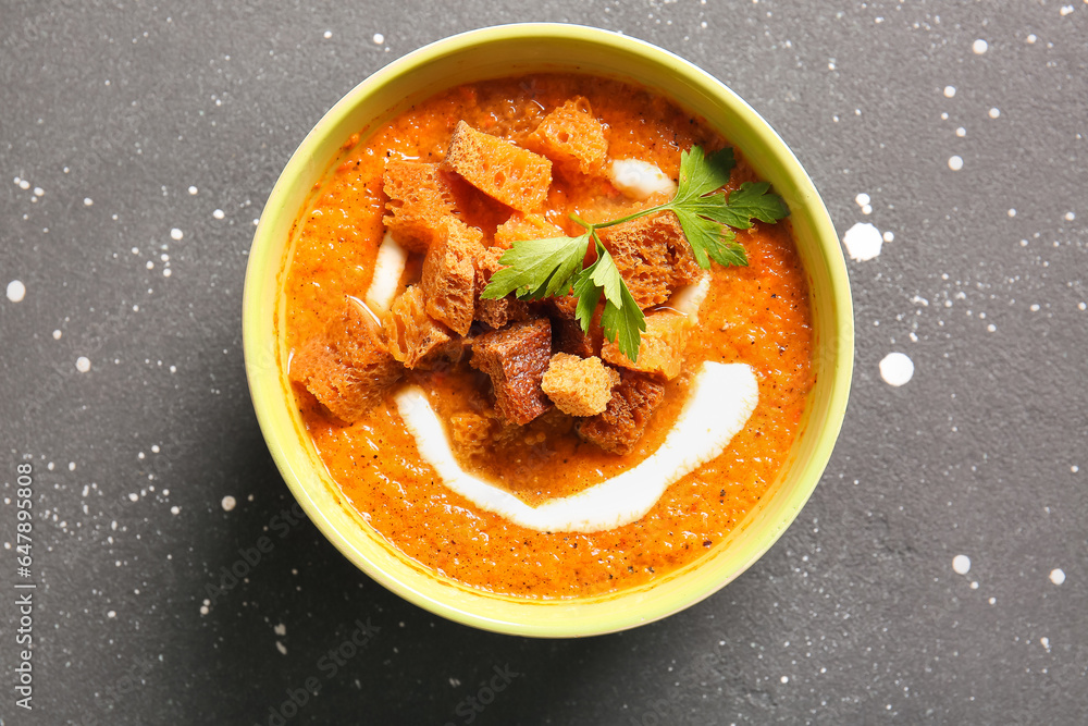 Bowl of tasty cream soup with croutons on black background