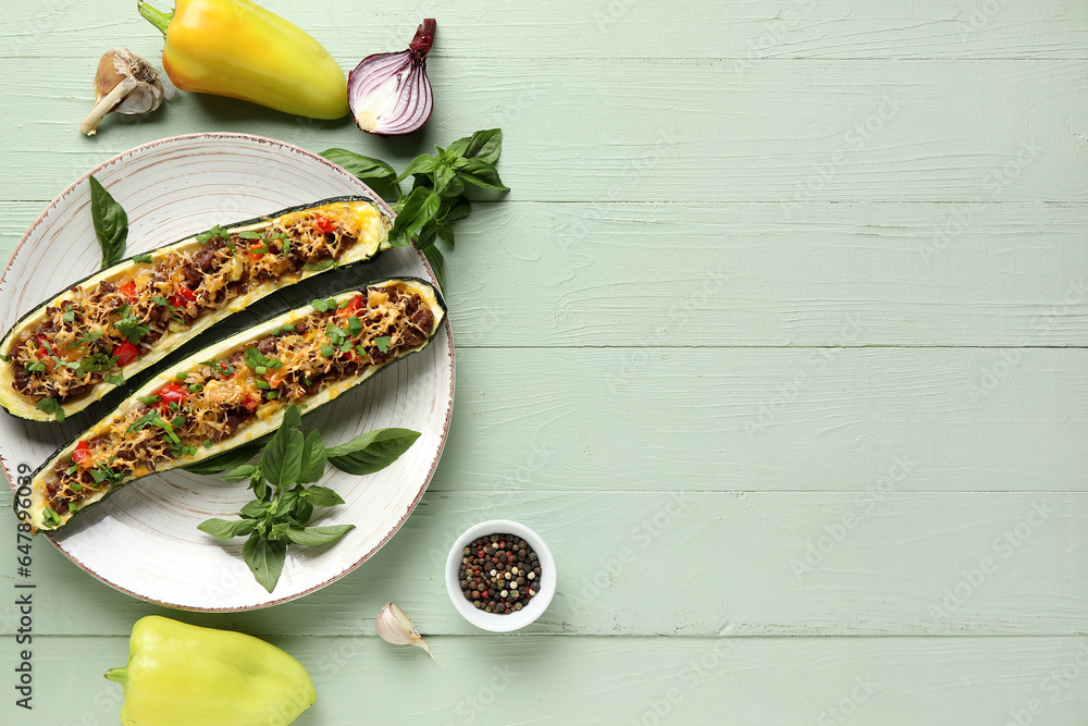 Plate with meat stuffed zucchini boats, bell pepper, garlic and onion on green wooden background