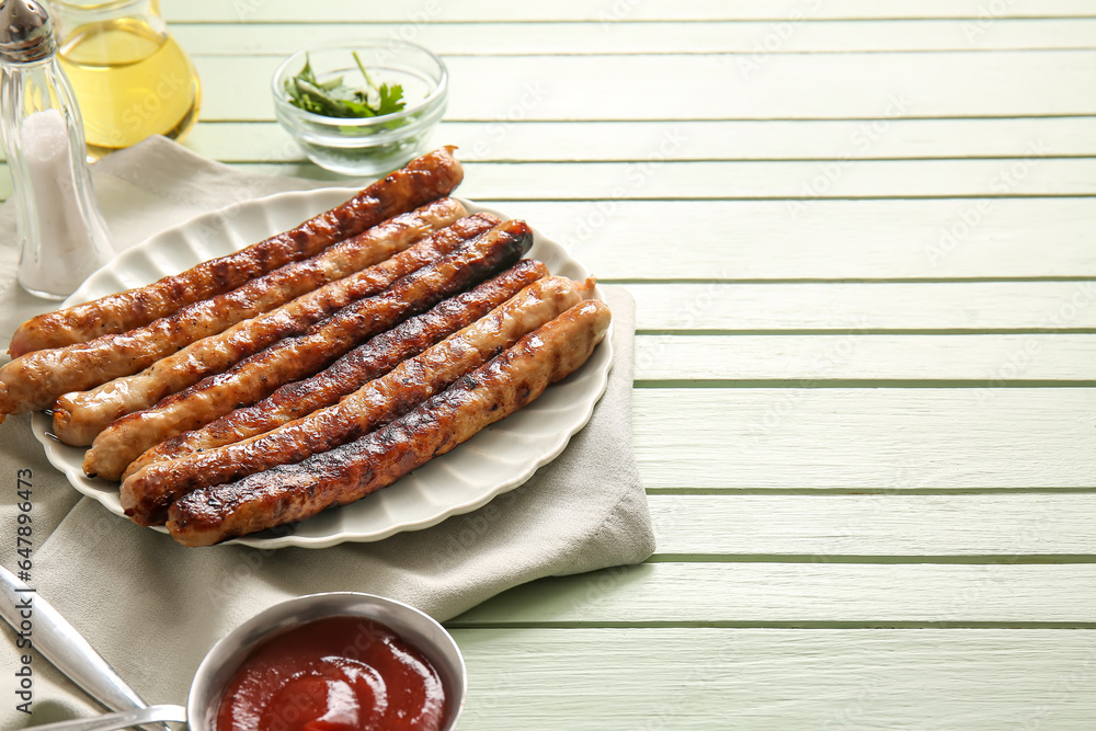 Plate of tasty grilled sausages on green wooden background