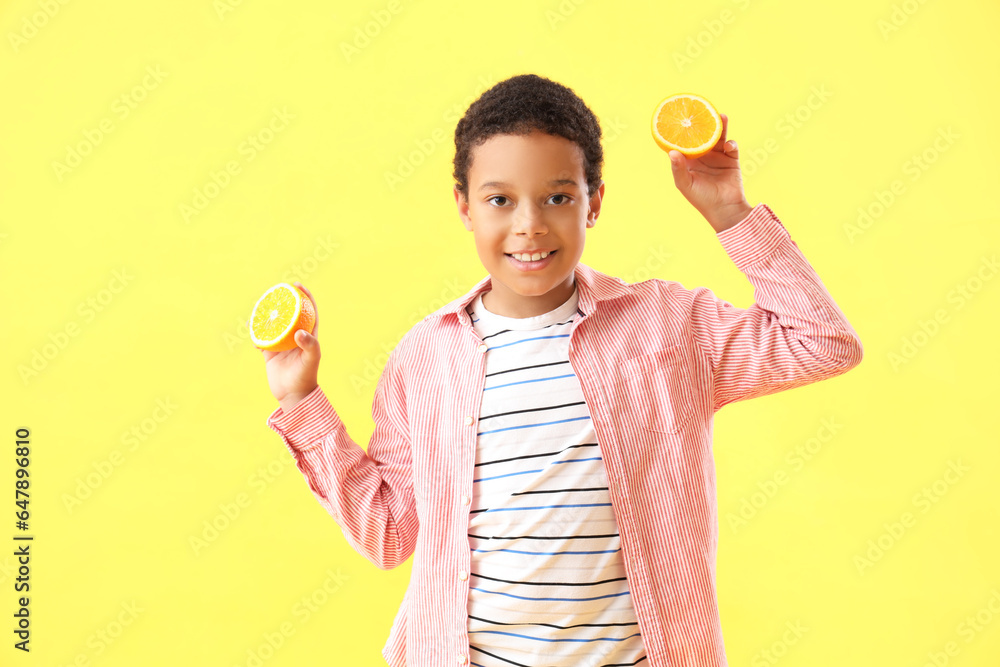 Little African-American boy with slices of orange on yellow background