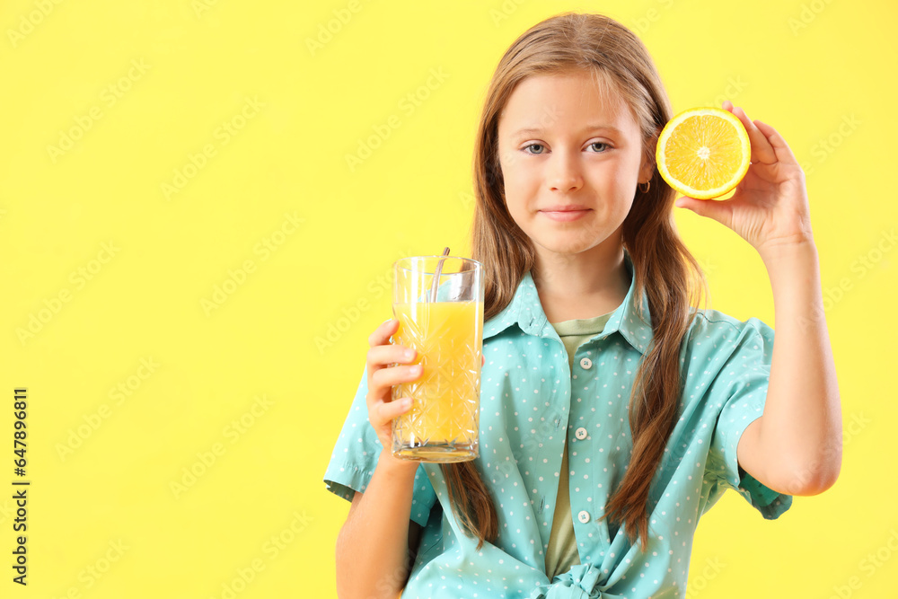 Little girl with orange and glass of fresh juice on yellow background