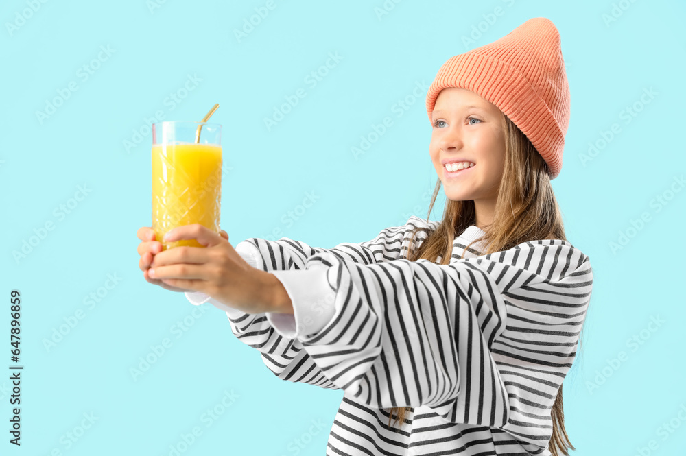 Little girl with glass of fresh citrus juice on blue background