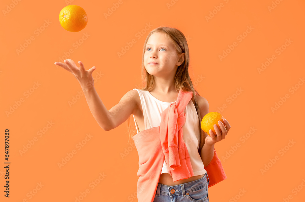 Little girl with fresh oranges on orange background