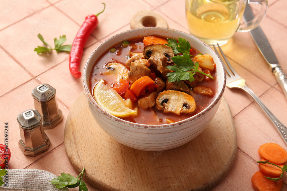 Bowl of tasty beef stew on beige tile background