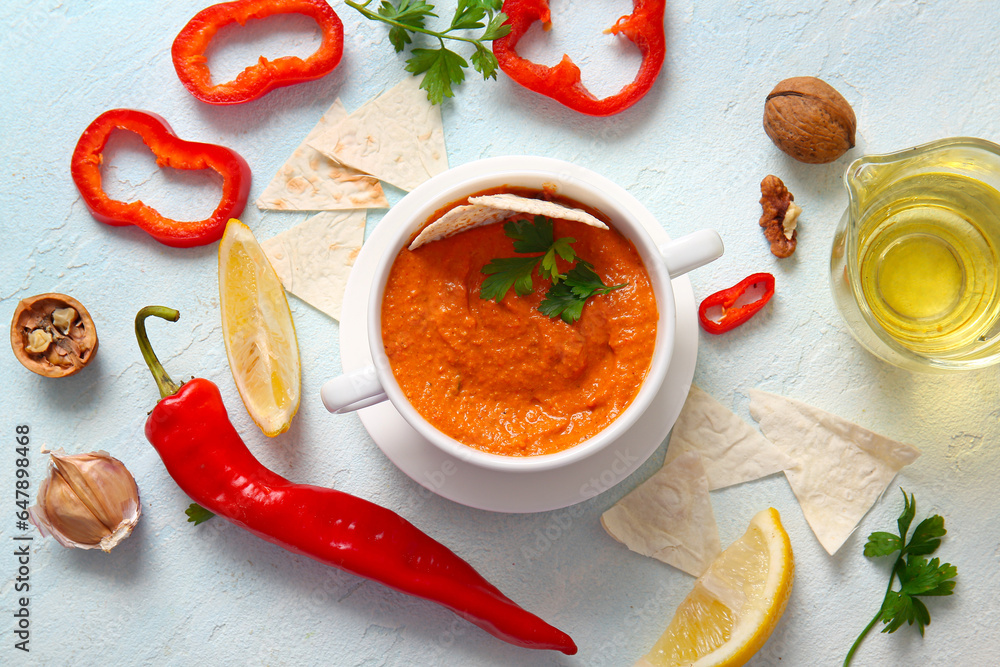 Pot of tasty muhammara and ingredients on white background