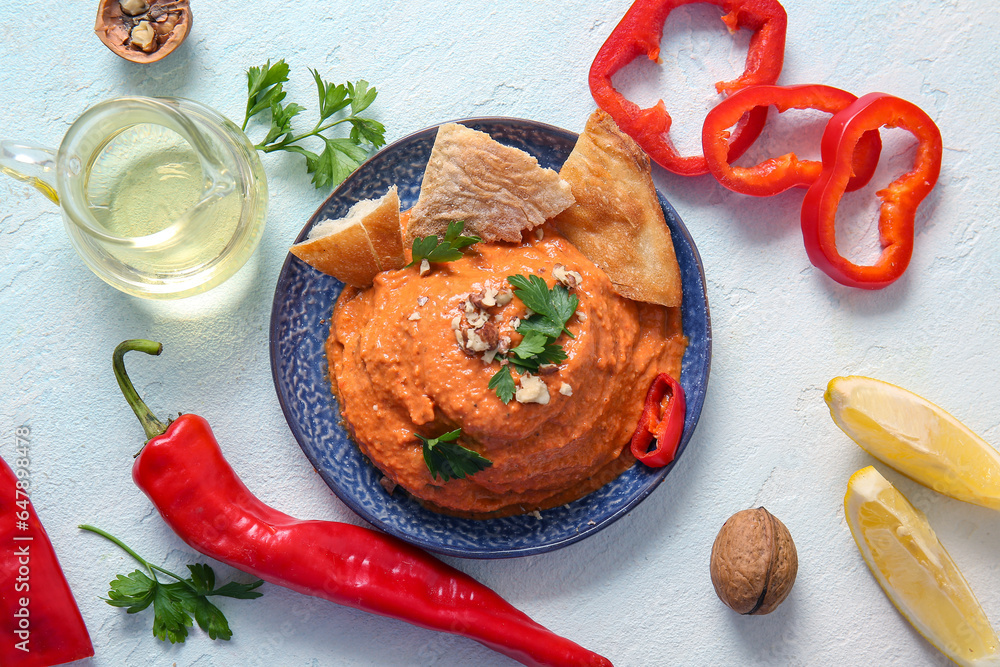 Plate of tasty muhammara and ingredients on white background