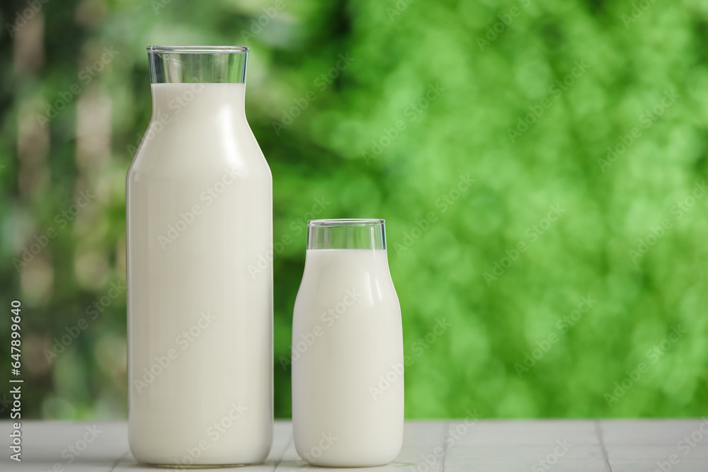 Bottles of fresh milk on white tile table outdoors