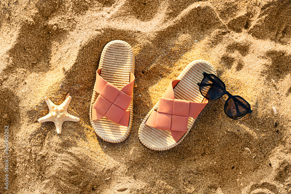 Stylish flips flops with sunglasses and starfish on sand at resort