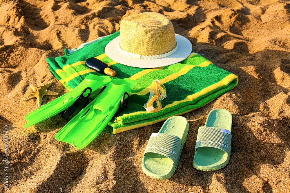 Stylish flips flops with beach accessories on sand at resort