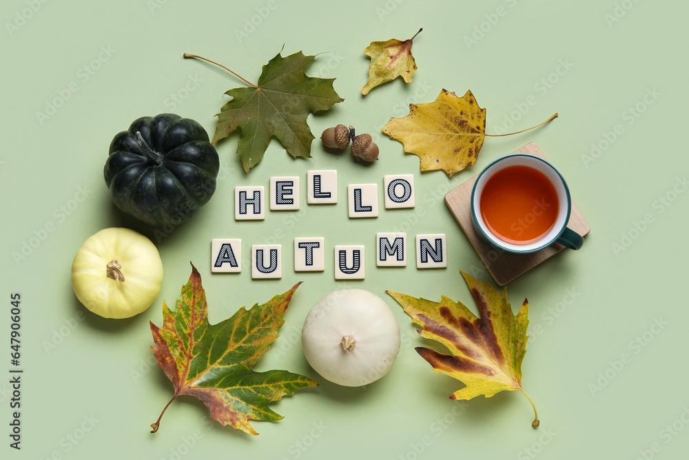 Composition with text HELLO AUTUMN, cup of tea, pumpkins and leaves on color background