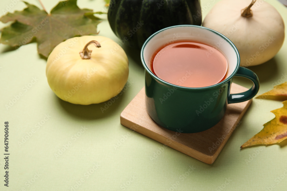 Cup of tea, pumpkins and autumn leaves on color background, closeup