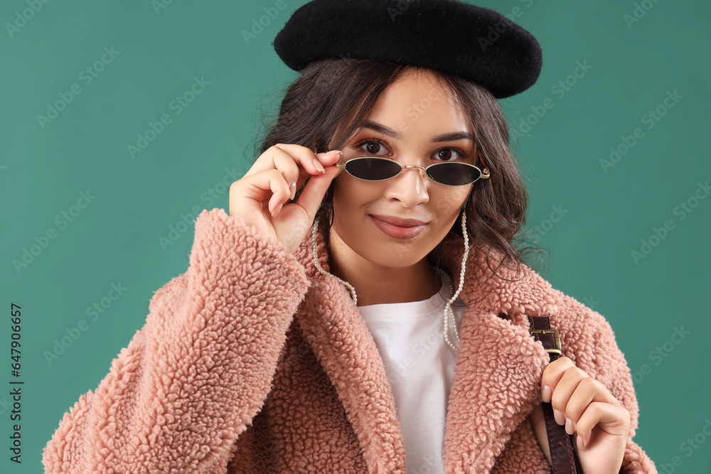 Stylish young Asian woman in fall clothes on green background, closeup