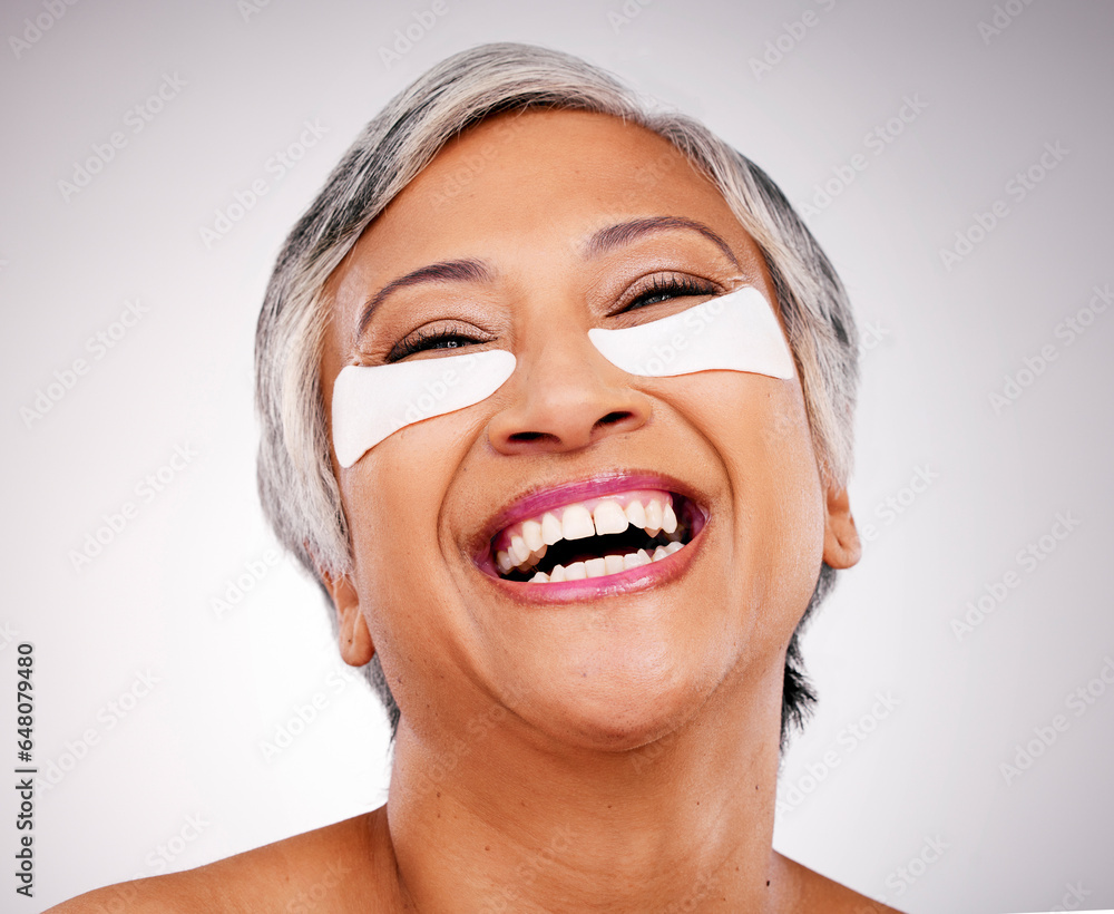 Mature, happy woman and face with eye patches in skincare, cosmetics or anti aging against a studio background. Senior female person or model smile with pads on eyes for facial treatment or routine