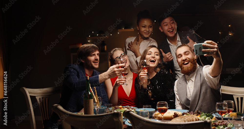 Positive multiethnic student friends celebrating together, having video chat with their friends or parents, cheering about christmas or graduation and smiling - communication, real people 