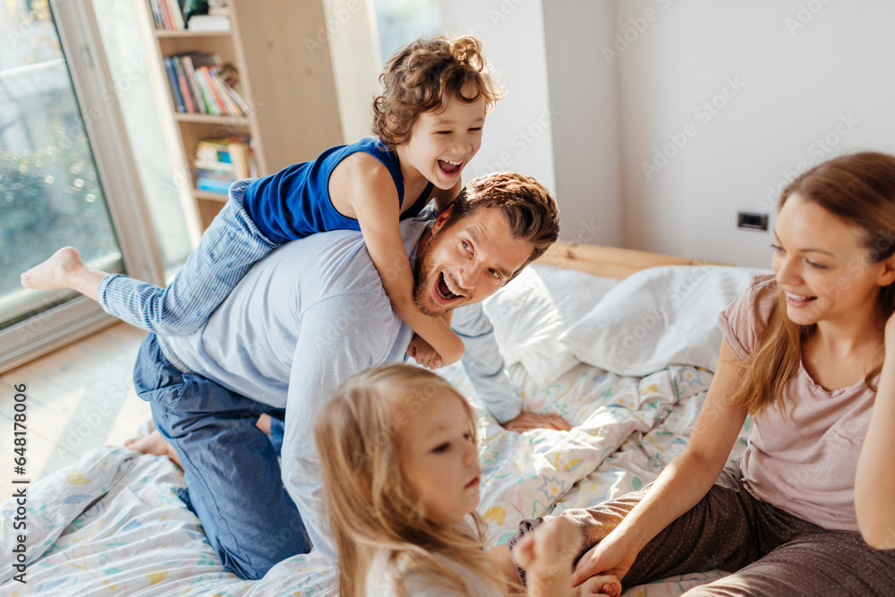 Young caucasian family having fun and playing together in the bedroom in their pyjamas