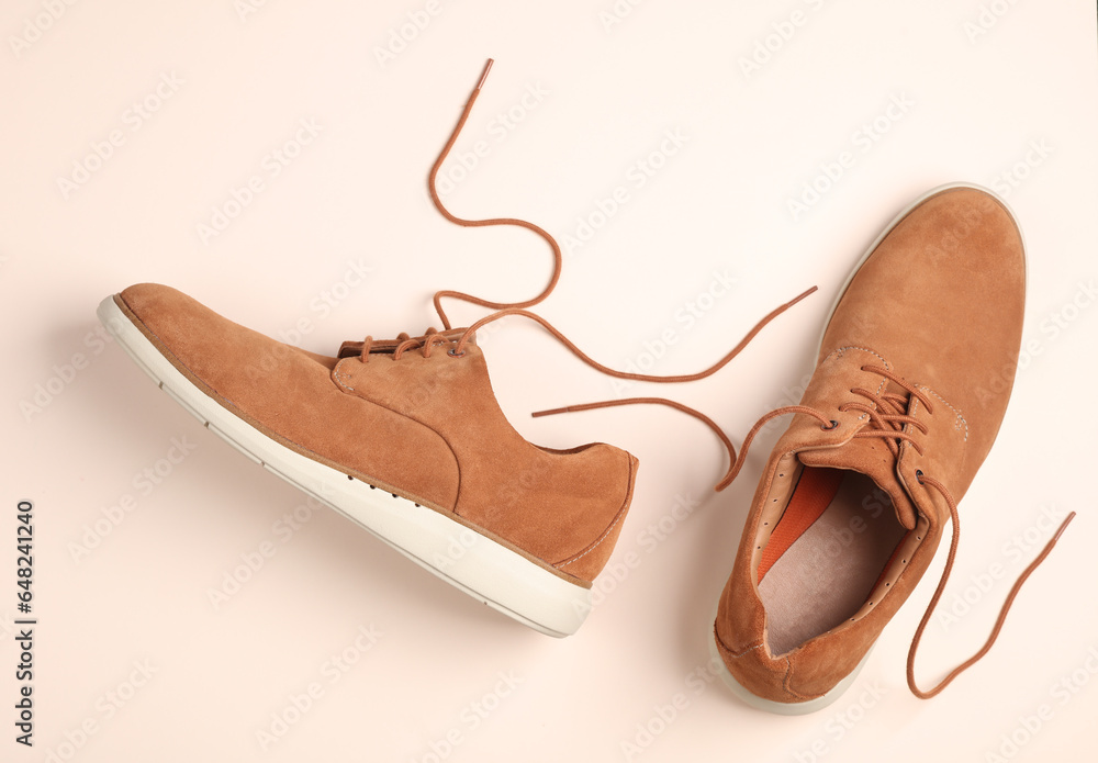 Mens suede shoes with untied laces on beige background