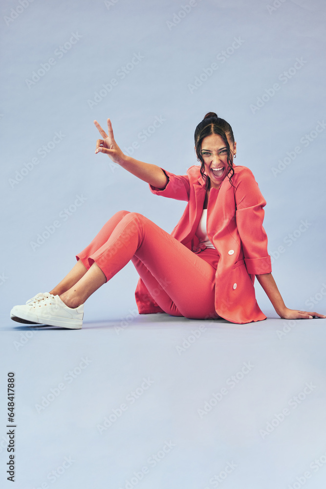 Fashion, woman and peace sign on floor in studio with happiness and makeup for beauty, aesthetic and cosmetics with mockup. Smile, person and creative clothes on purple background with confidence