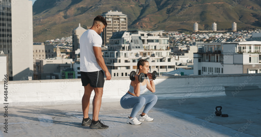 Personal trainer, fitness and a woman outdoor with dumbbells for exercise, workout or training rooftop. Couple of friends in urban city for squats, strong muscle or bodybuilder and lifting weights