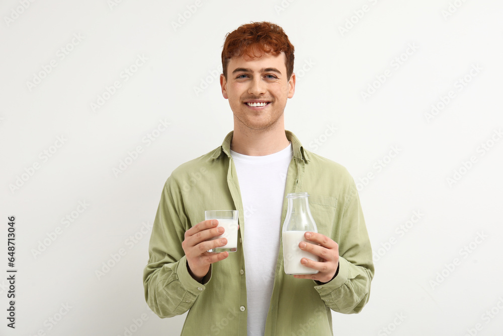 Young man with glass and bottle of milk on white background