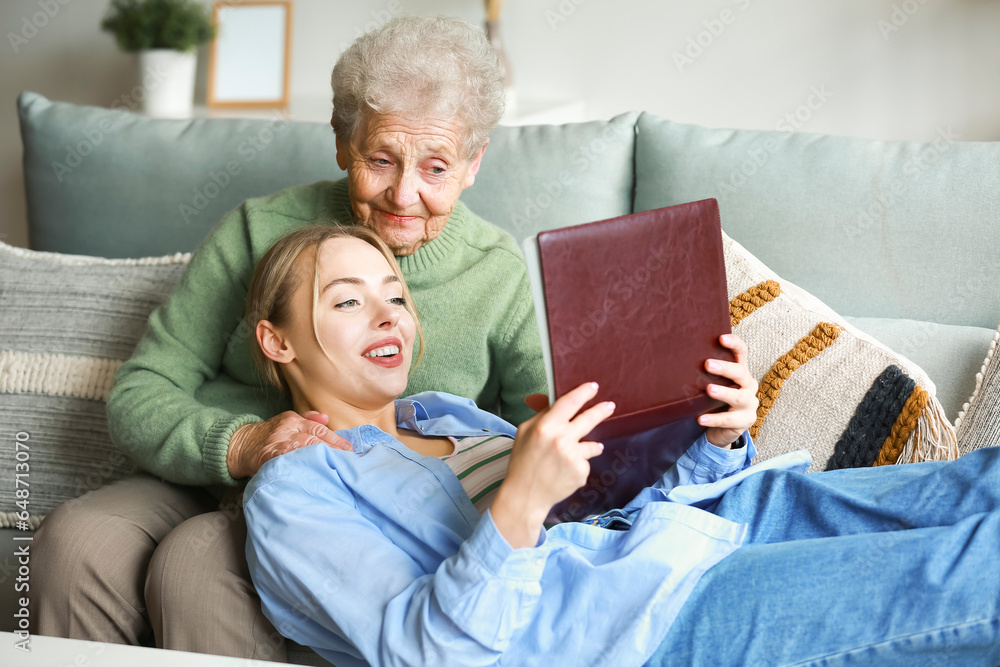 Young woman and her grandmother with photo album at home