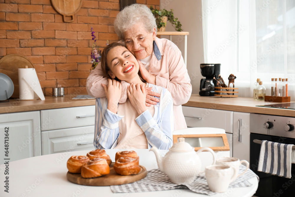 Senior woman hugging her grandmother in kitchen