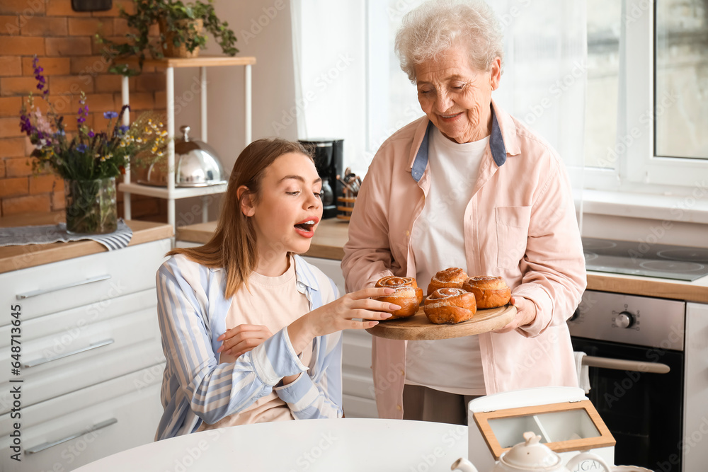 Young woman with her grandmother eating buns in kitchen