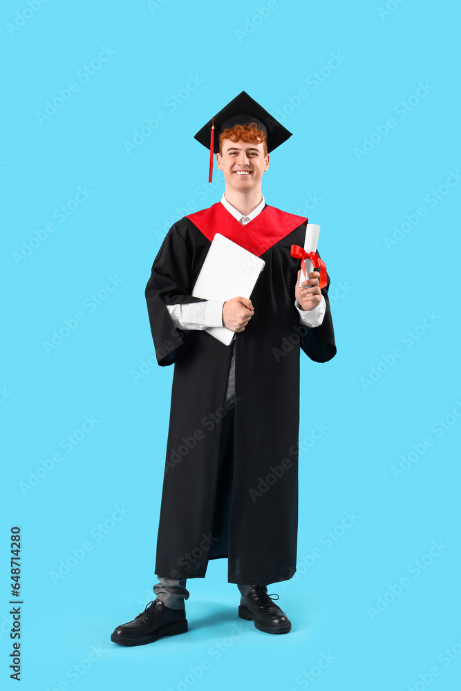 Male graduate student with diploma and laptop on blue background