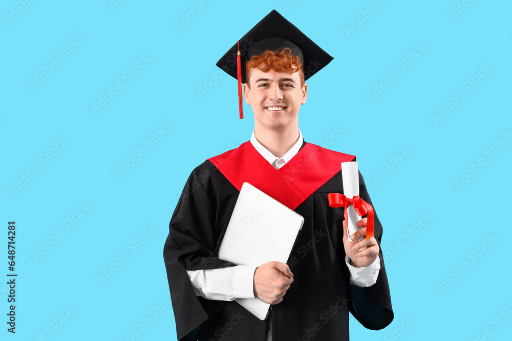 Male graduate student with diploma and laptop on blue background