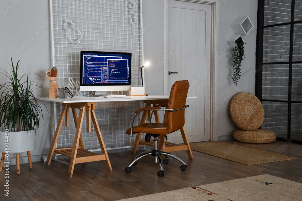 Programmers workplace with computer monitor and glowing lamp in office