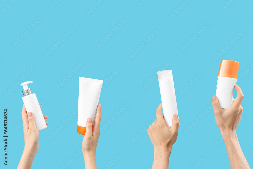 Female hands with bottles of sunscreen cream on blue background