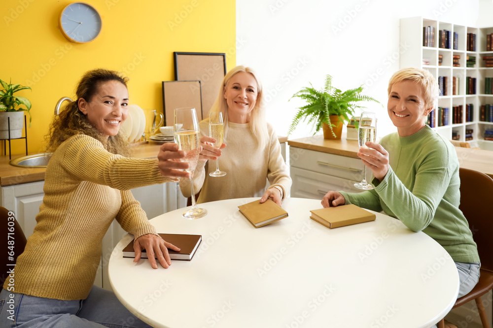 Mature women with champagne taking part in book club at home