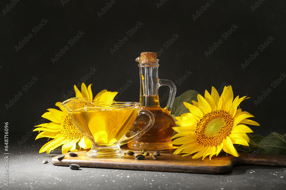 Decanter and gravy boat of sunflower oil with seeds on black background