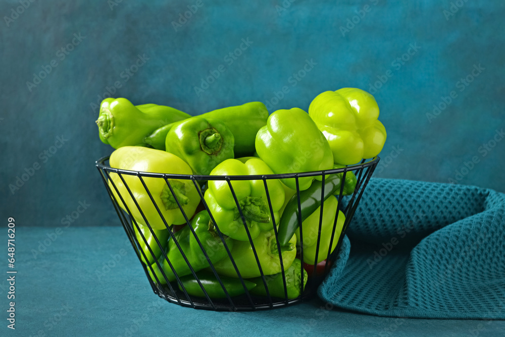 Basket with different fresh peppers on blue background