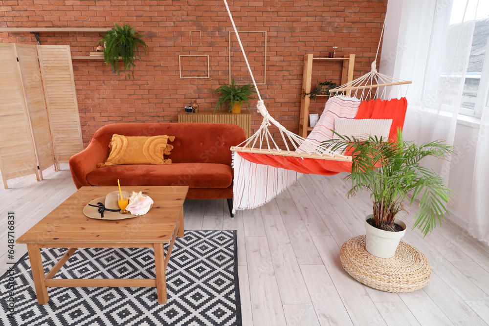 Interior of stylish living room with brown sofa, hammock and coffee table