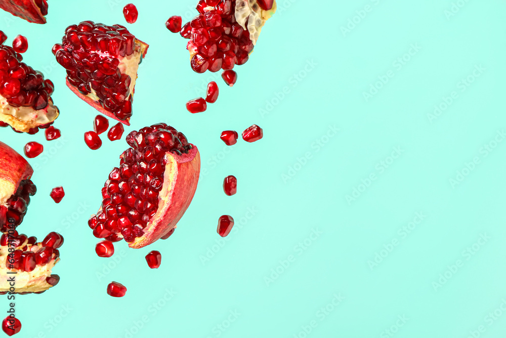 Flying fresh pomegranates with seeds on turquoise background