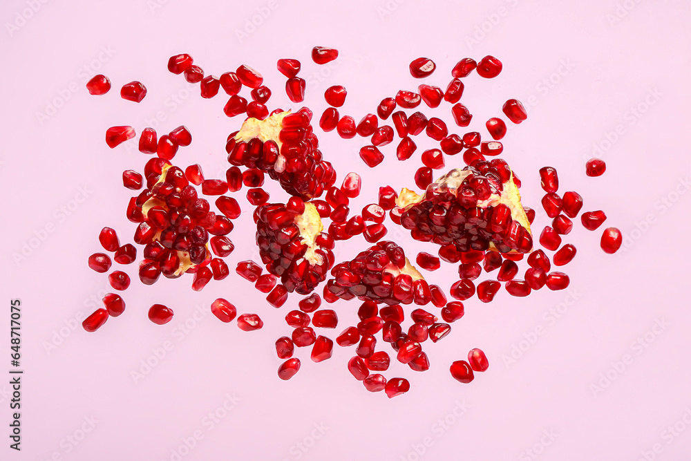 Flying fresh pomegranates with seeds on lilac background