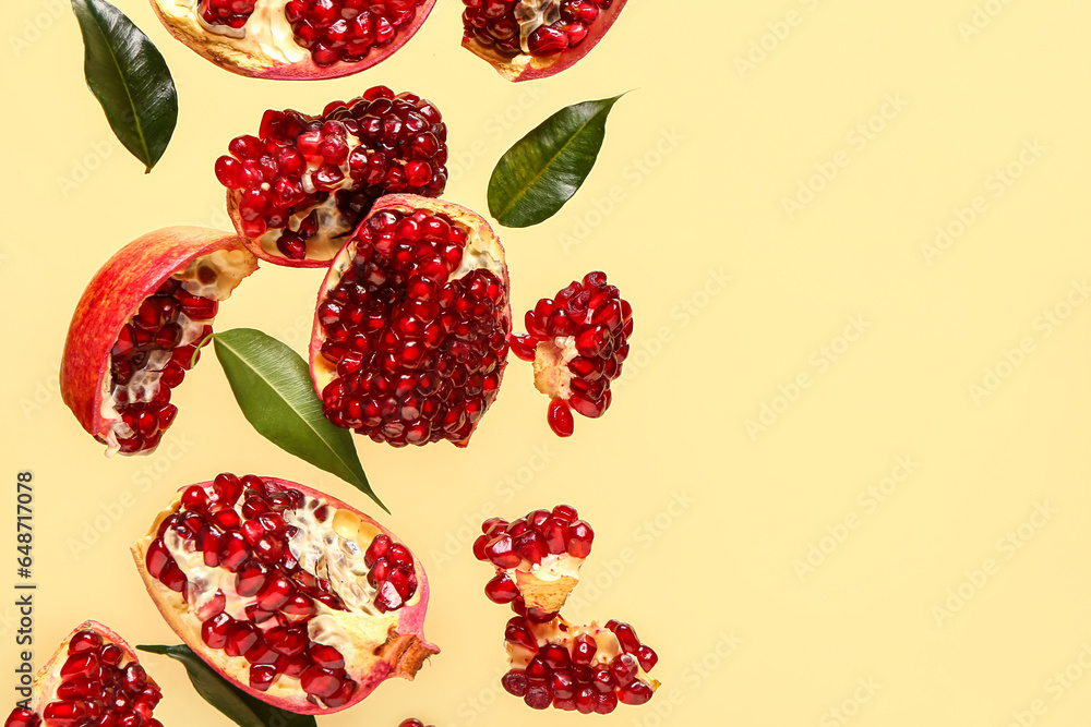 Flying fresh pomegranates and leaves on yellow background