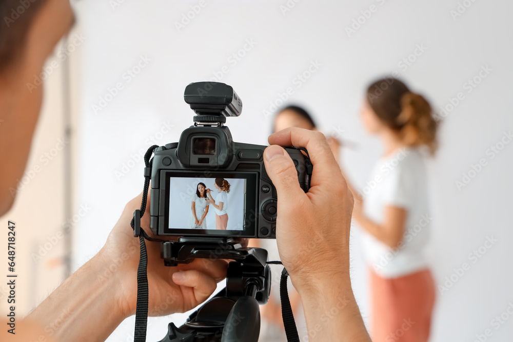 Male photographer taking picture of young Asian woman in studio, closeup