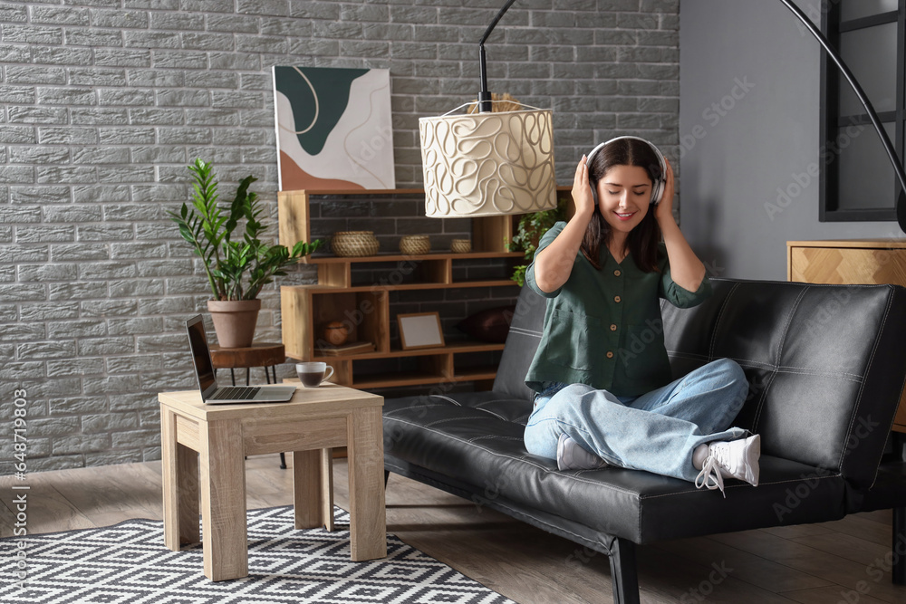 Young woman listening to music on sofa in living room